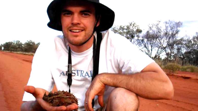 A younger Dr Steven Sushinsky in outback Australia holding a lizard.