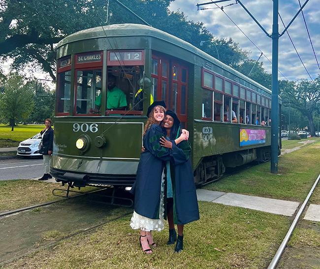 Kelly hugging a friend in front of tram at graduation